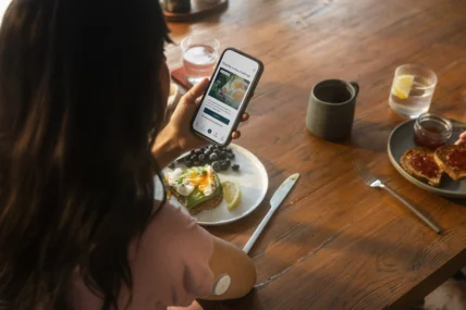woman looks on her phone while eating