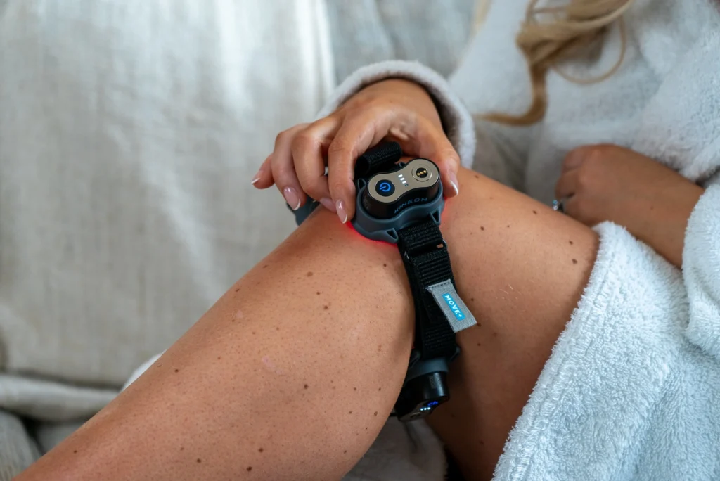woman wears a Kineon red light therapy device on her knee