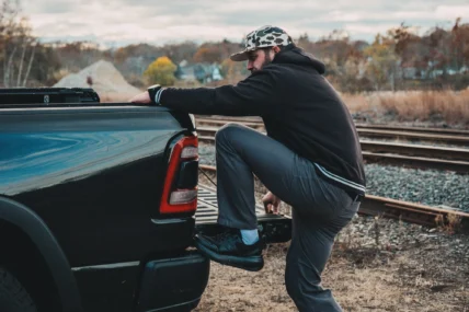 man climbs on a pickup trick wearing Stoke sneakers