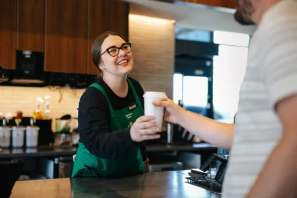 Starbucks barista hands a man a drink