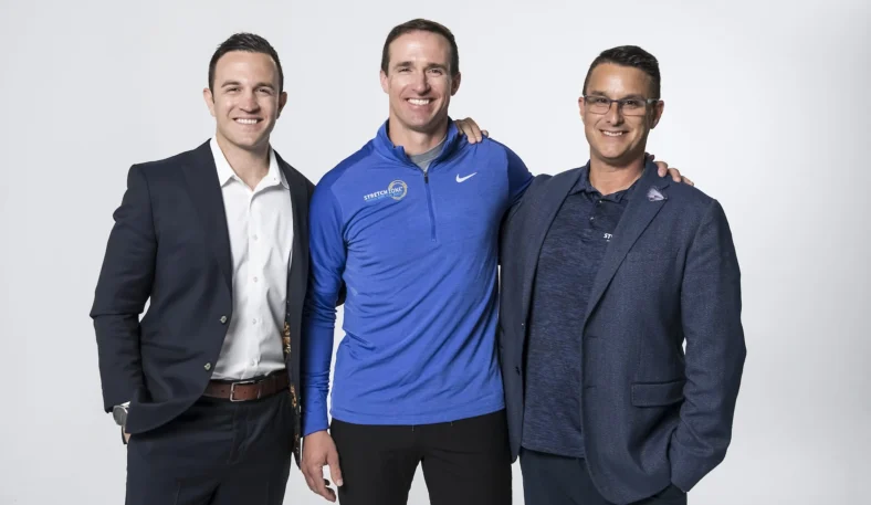 Drew Brees poses with Stretch Zone's Tony Zaccario and Jorden Gold