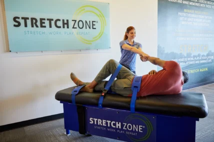 woman stretches a male client at a Stretch Zone